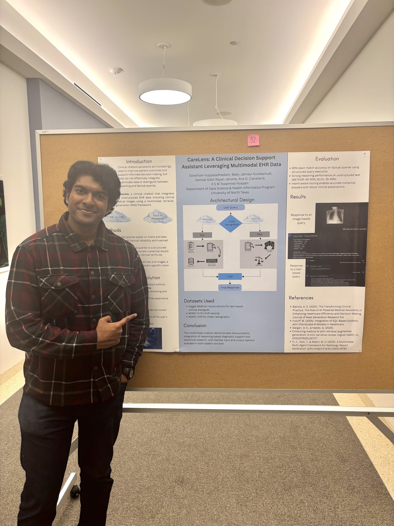 Samuel pointing at the CareLens poster on a conference board
